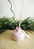 Petit vase diffuseur de parfum rose pâle.